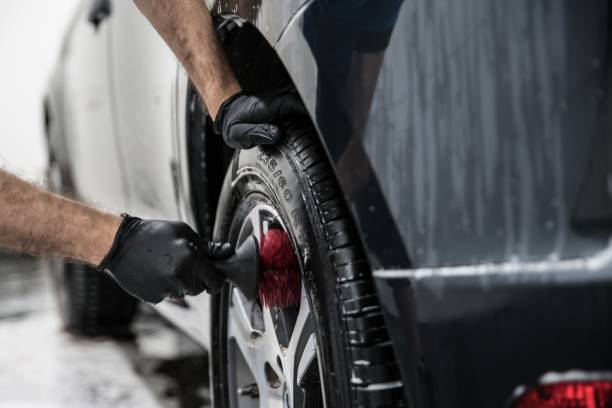man cleaning car wheel with brush. - car wash car cleaning washing imagens e fotografias de stock