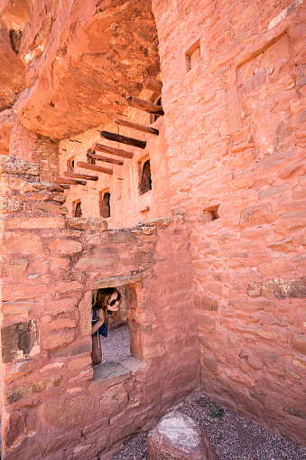 Teenage girl peeks through a window while exploring Manitou Cliff Dwelling, Manitou Springs, Colorado, USA