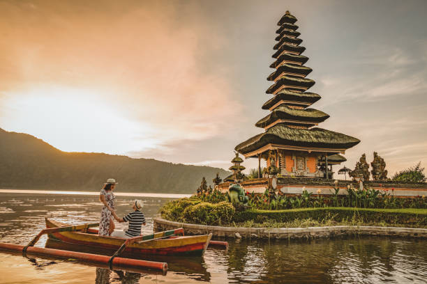 You'll always be my forever Happy romantic couple in love relaxing on honeymoon. The Ulun Danu Tamblingan Temple is located in the north side of Bali, in a Tamblingan lake. Tourist couple enjoying the lake. Photo of a couple on a boat in the lake at sunset, looking at each other. bali stock pictures, royalty-free photos & images