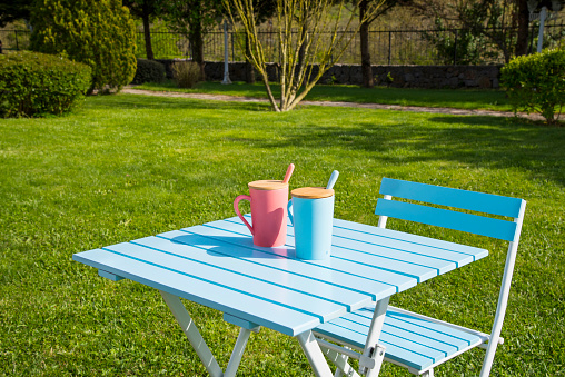 Colorful pink and blue coffee mugs on table in garden