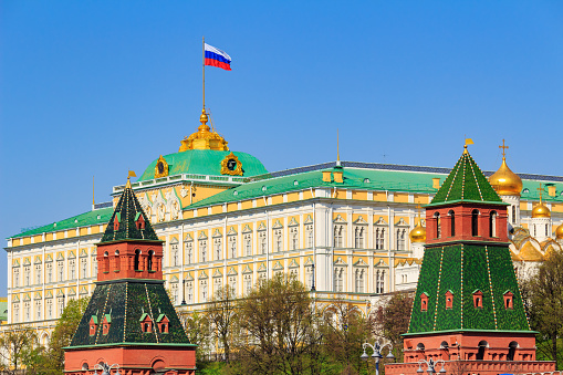 Moscow, Russia - May 01, 2019: Building of Grand Kremlin Palace with waving flag of Russian Federation on the roof against Moscow Kremlin towers on a blue sky background