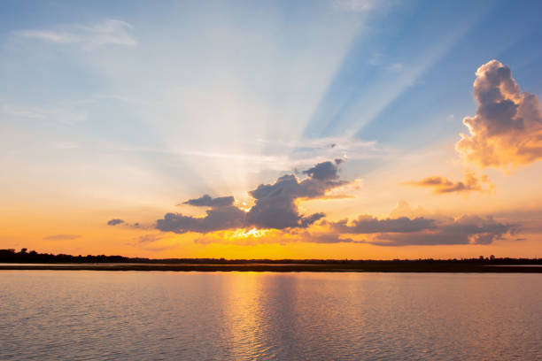 istock Sunset reflection lagoon. beautiful sunset behind the clouds and blue sky above the over lagoon landscape background. dramatic sky with cloud at sunset 1160089362