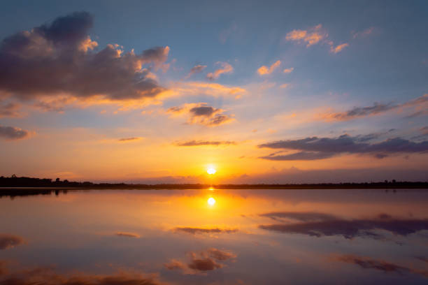 istock Sunset reflection lagoon. beautiful sunset behind the clouds and blue sky above the over lagoon landscape background. dramatic sky with cloud at sunset 1160090893