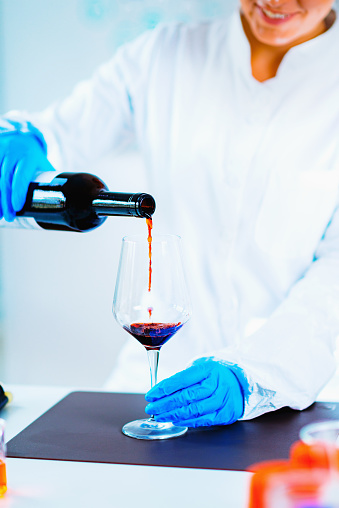 Quality control expert inspecting red wine in the laboratory
