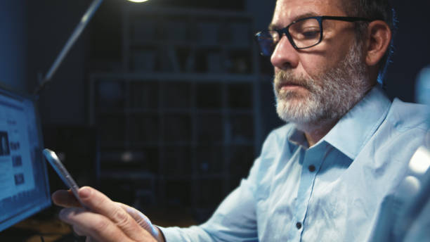istock Businessman with glasses working focused in office at night, authentic wide angle shot 1160102072