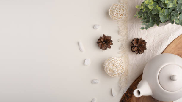 White porcelain teapot with accessories on a wooden board on a white table. View from above. Copy space