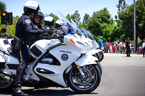 Huntington Beach, CA - July 4, 2019: Motorcycle police officers direct crowds and traffic during parade