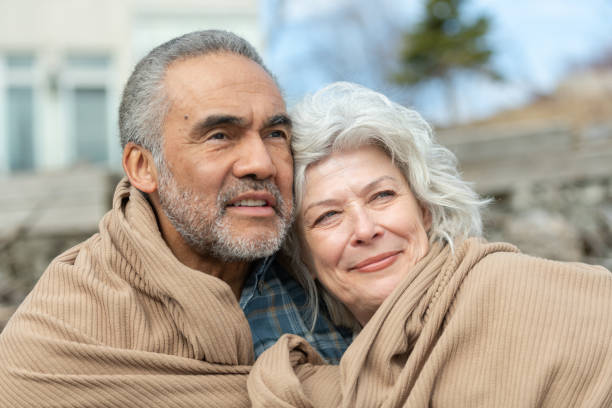 istock Senior couple wrapped in a blanket on a beach 1160108762