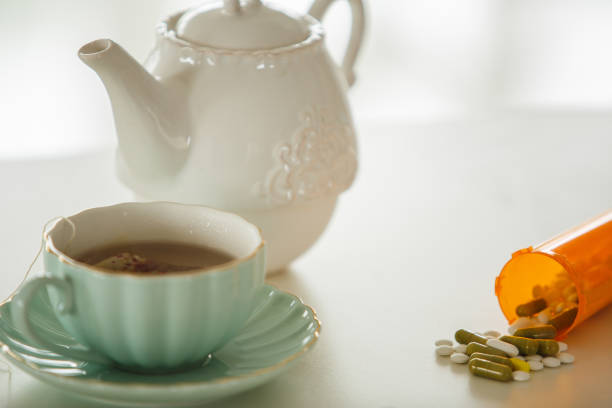 Close up shot of bottle of prescription drugs spilling out and lying next to a tea cup and tea pot against flu.