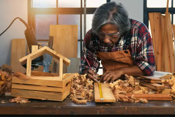 senior male carpenter concentrating on making woodwork in workshop as hobby