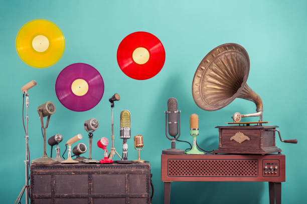 old retro microphones, antique gramophone phonograph turntable with brass horn, flying multicolor lp vinyl record discs front blue background. nostalgia music concept. vintage style filtered photo - radio gramophone imagens e fotografias de stock