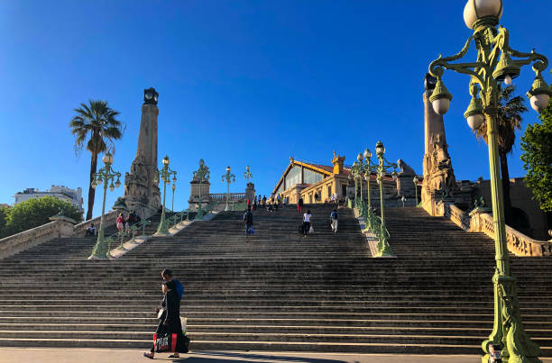 Marseille, France: The grand staircase at Marseille Saint Charles train station at dusk (golden hour) with people walking by. The station was opened in 1926.