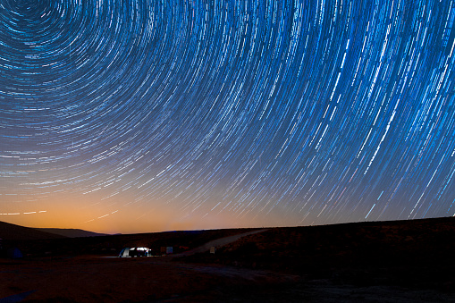 Camper van under a starry night with star trails. Taken near Mizpe Ramon in southern Israel. comprised of almost 100 still images.