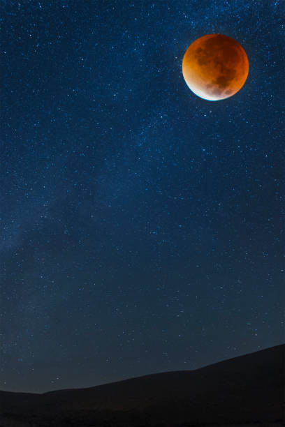 istock Desert scene with starry skies and a bloody moon in eclipse 1160121727