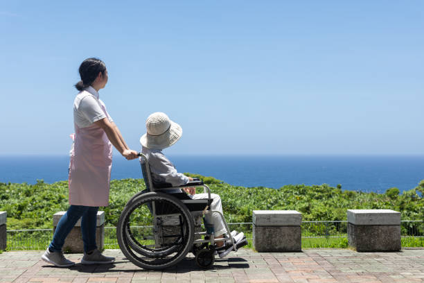 Senior and care helper taking a walk with a wheelchair Japanese elderly care image pushing photos stock pictures, royalty-free photos & images