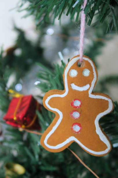istock Image of artificial Christmas tree homemade gingerbread man, gingerbread men decorations made from salt dough, baked like cookies and painted by hand with acrylic / poster paints, fake Xmas tree decorated with fairy lights, silver tinsel, baubles, snowmen 1160135355