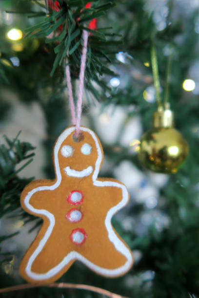istock Image of artificial Christmas tree homemade gingerbread man, gingerbread men decorations made from salt dough, baked like cookies and painted by hand with acrylic / poster paints, fake Xmas tree decorated with fairy lights, silver tinsel, baubles, snowmen 1160135359