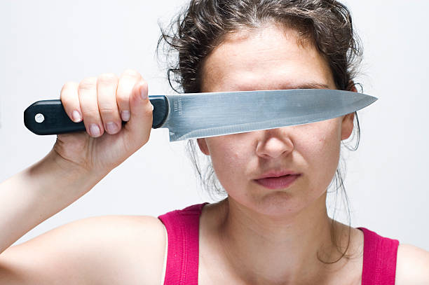 Close up of man's hand holding knife, scared woman in background