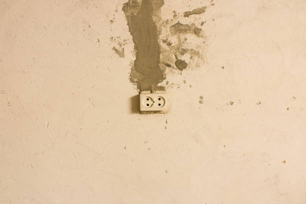 istock Electrical outlet on the old concrete wall. Isolated on light background. 1160138381