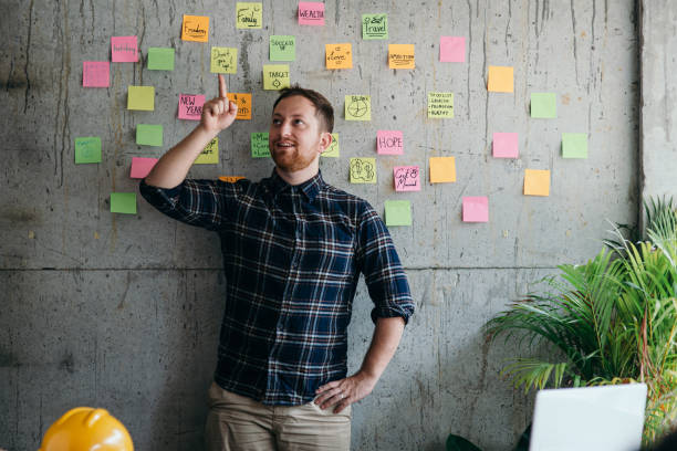 istock Happy engineer man present his sticky notes chart on cement wall.  Entrepreneur concept 1160140223