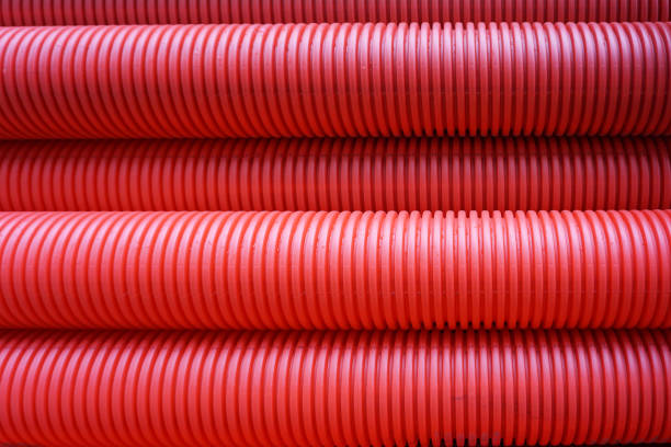 Many red corrugated pipes for laying communications. Industrial background.