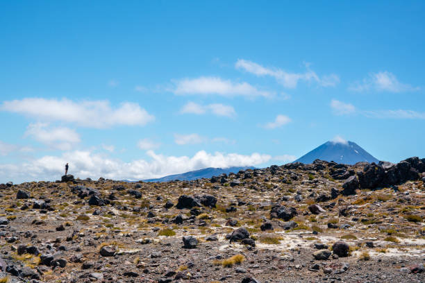 istock Tiny person standing on a rock photographing the volcano 1160141121