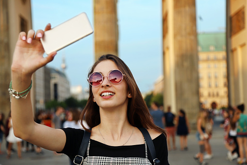 Happy young girl taking a selfie with a smartphone on Brandenburg Gate