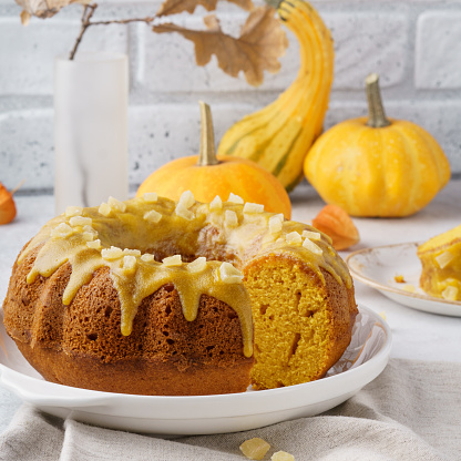 Pumpkin bundt cake topped with sugar glaze and candied fruits. Holiday seasonal pastry.