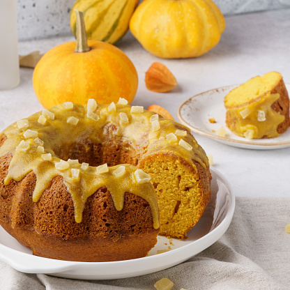 A piece of sweet pumpkin bundt cake topped with sugar glaze and candied fruits.