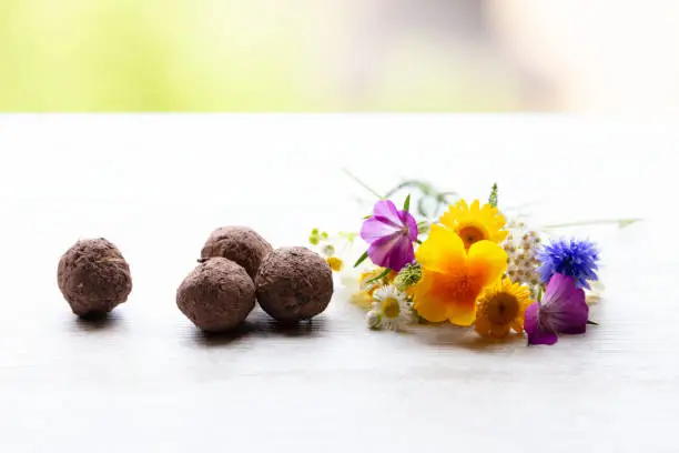 seed balls or seed bombs with various blossoms on a white, wooden background