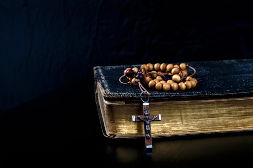 Cuentas del Rosario y libro de oración. Rosario y libro de liturgia de la Iglesia Católica sobre fondo oscuro. photo