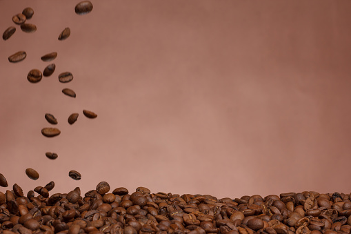 Falling coffee beans on a brown background.