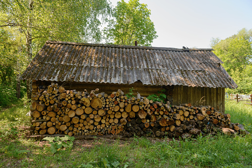 A log wall for firewood in an old wooden house near the cemetery