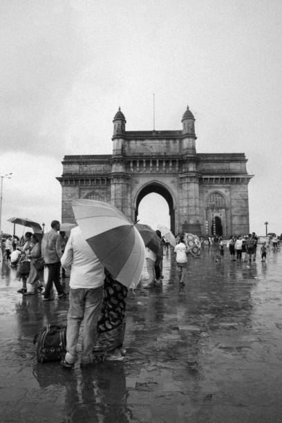 turistas que visitam a porta de india em um dia chuvoso, mumbai - vertical gateway to india famous place travel destinations - fotografias e filmes do acervo