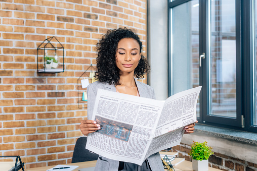 attractive african american Casual businesswoman reading Business newspaper in loft office