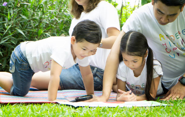 istock Children With Parents Looking At Drawing In Park 1160167875