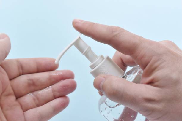 istock Close-Up Of Hand Holding Soap Dispenser Over Blue Background 1160177806