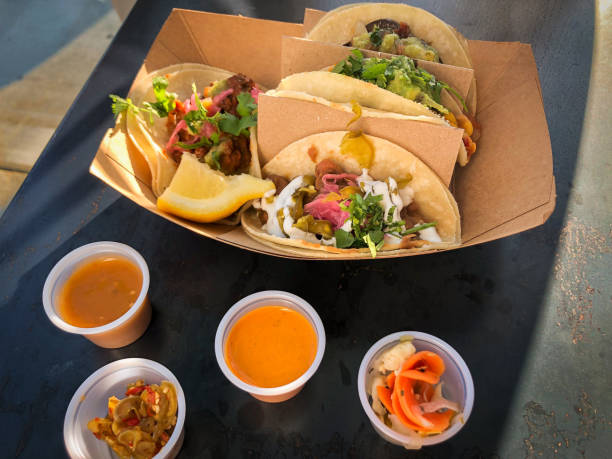 Takeout Containers of Vegan Tacos, Hot Sauces and Pickled Vegetables