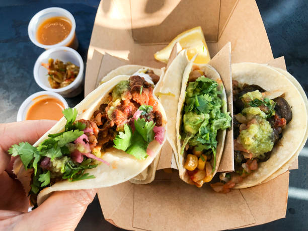 POV von Hand Holding Vegan Taco über Saucen und Gurken – Foto