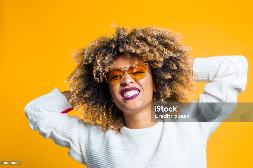 Pretty young woman enjoying on yellow background Portrait of pretty young african woman dancing and enjoying against yellow background Women Stock Photo