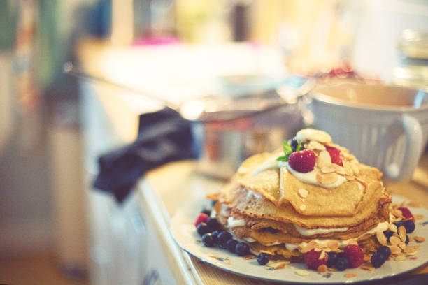 Stack of homemade thin pancakes in a messy kitchen