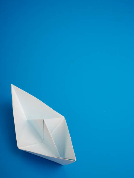 istock Single light white origami boat on blue background, Leadership concept 1160179525
