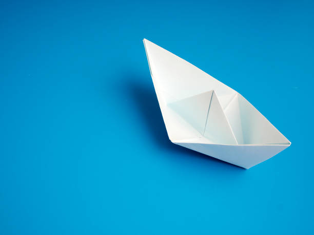 istock Single light white origami boat on blue background, Leadership concept 1160179534