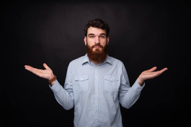 istock I don't know! Young bearded man gesturing with both hands he doesn't know. 1160180652