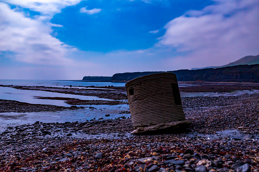 Long exposure night time photograph taken on Kimmeridge bay beach with old war fortification in foreground. Dorset, England