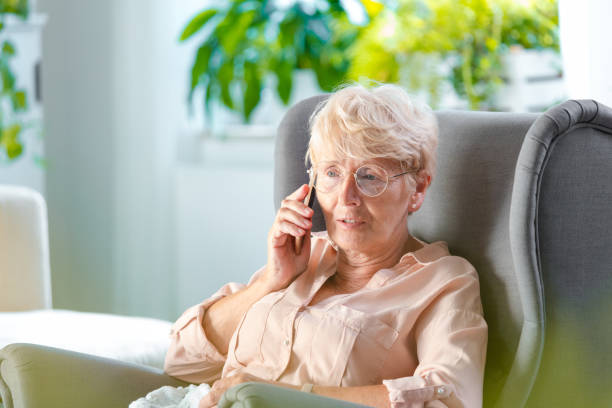 starsza kobieta rozmawia przez telefon komórkowy - old armchair women senior adult zdjęcia i obrazy z banku zdjęć