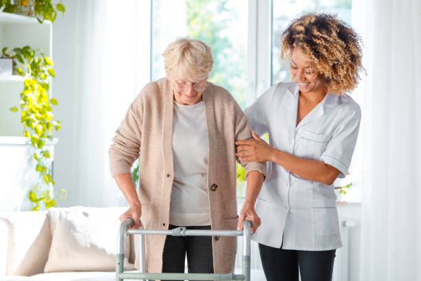Cheerful friendly nurse helping elderly woman Cheerful friendly nurse helping senior woman to use walking frame mobility walker stock pictures, royalty-free photos & images