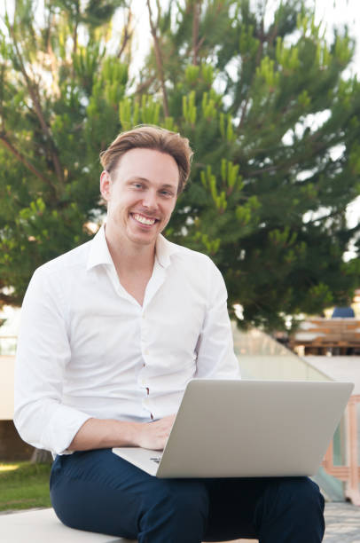 istock Smiling business man working on laptop in park 1160184872