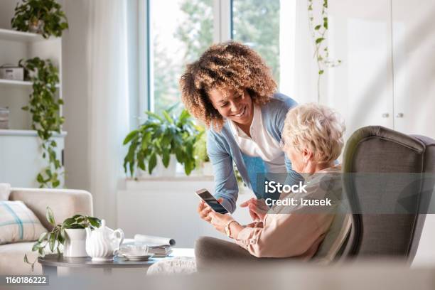Home Caregiver Assisting Senior Woman Stock Photo - Download Image Now - Senior Adult, Technology, Nurse