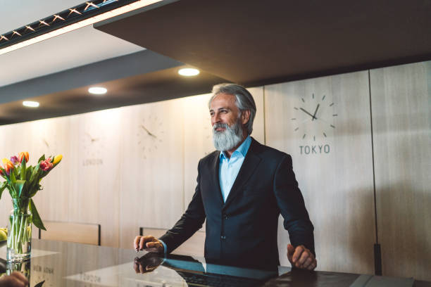 A male receptionist with gray hair and beard standing behind a hotel reception